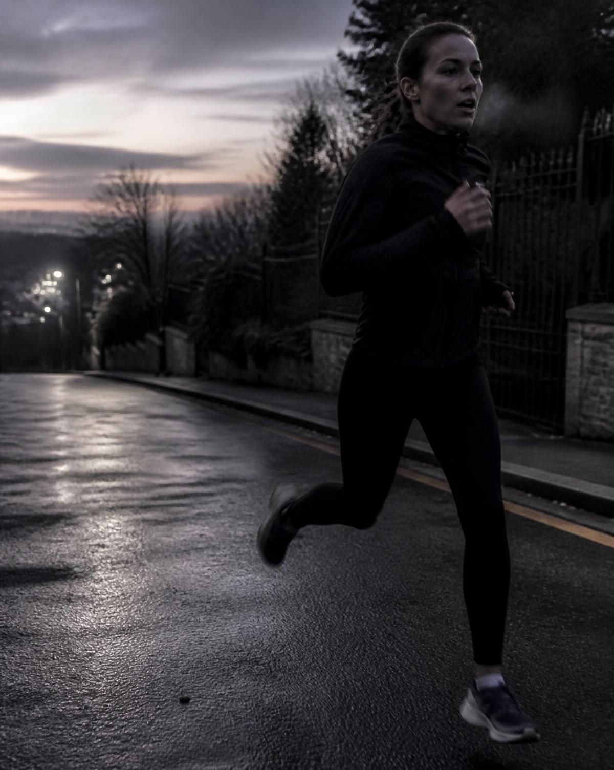 Runner working hard on wet asphalt at dawn