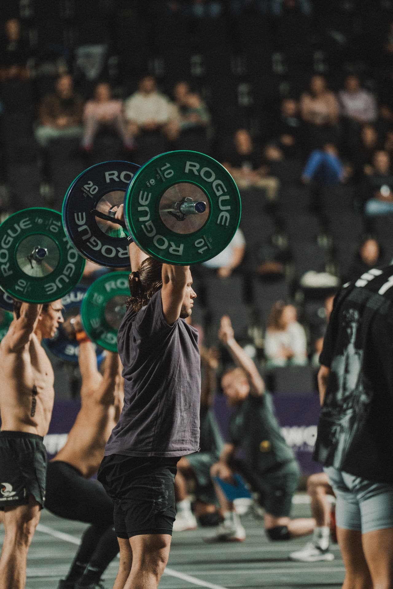 Athlete locking out a heavy barbell overhead on a competition floor
