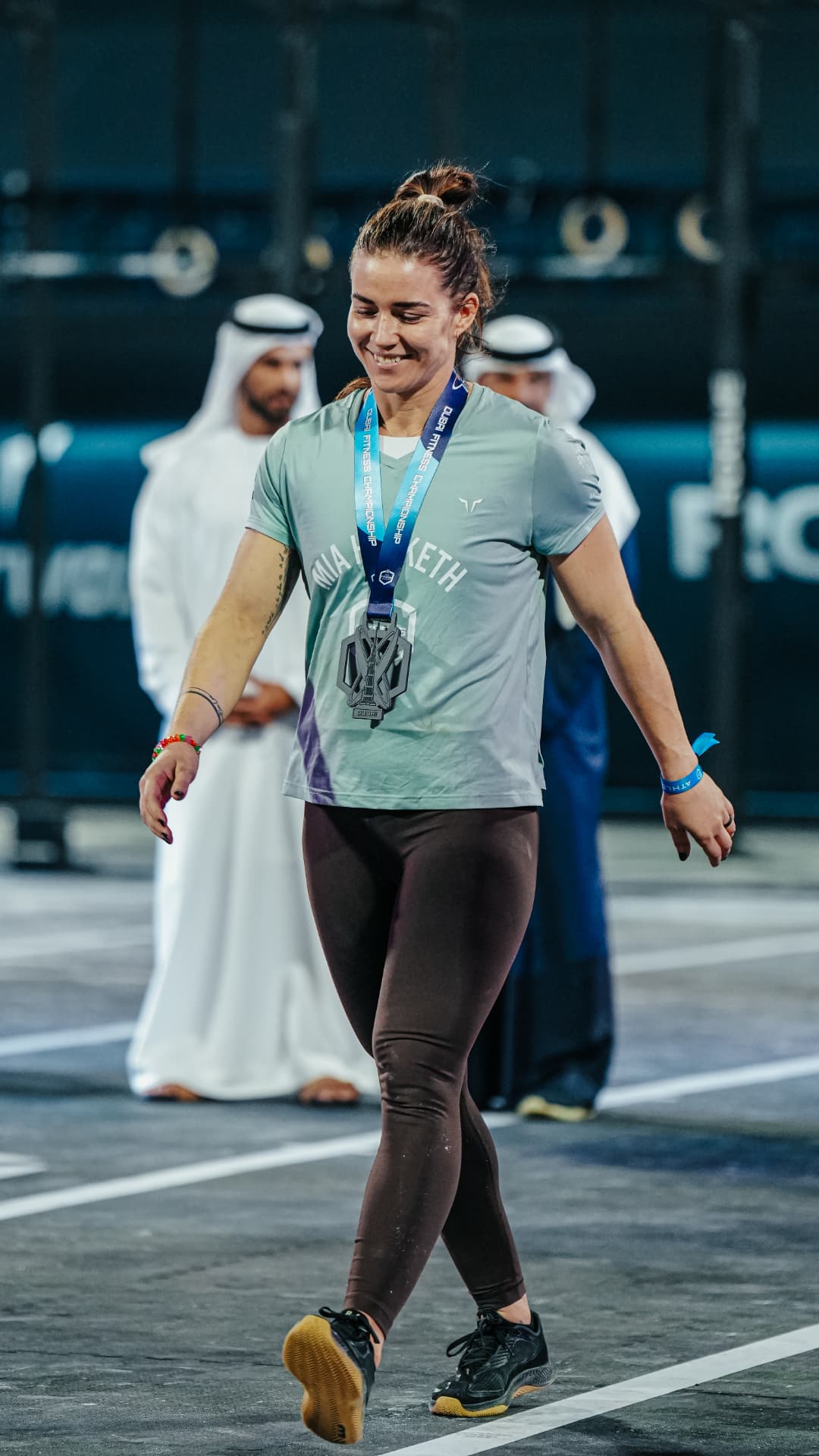 Athlete walking off the competition floor wearing a finisher medal